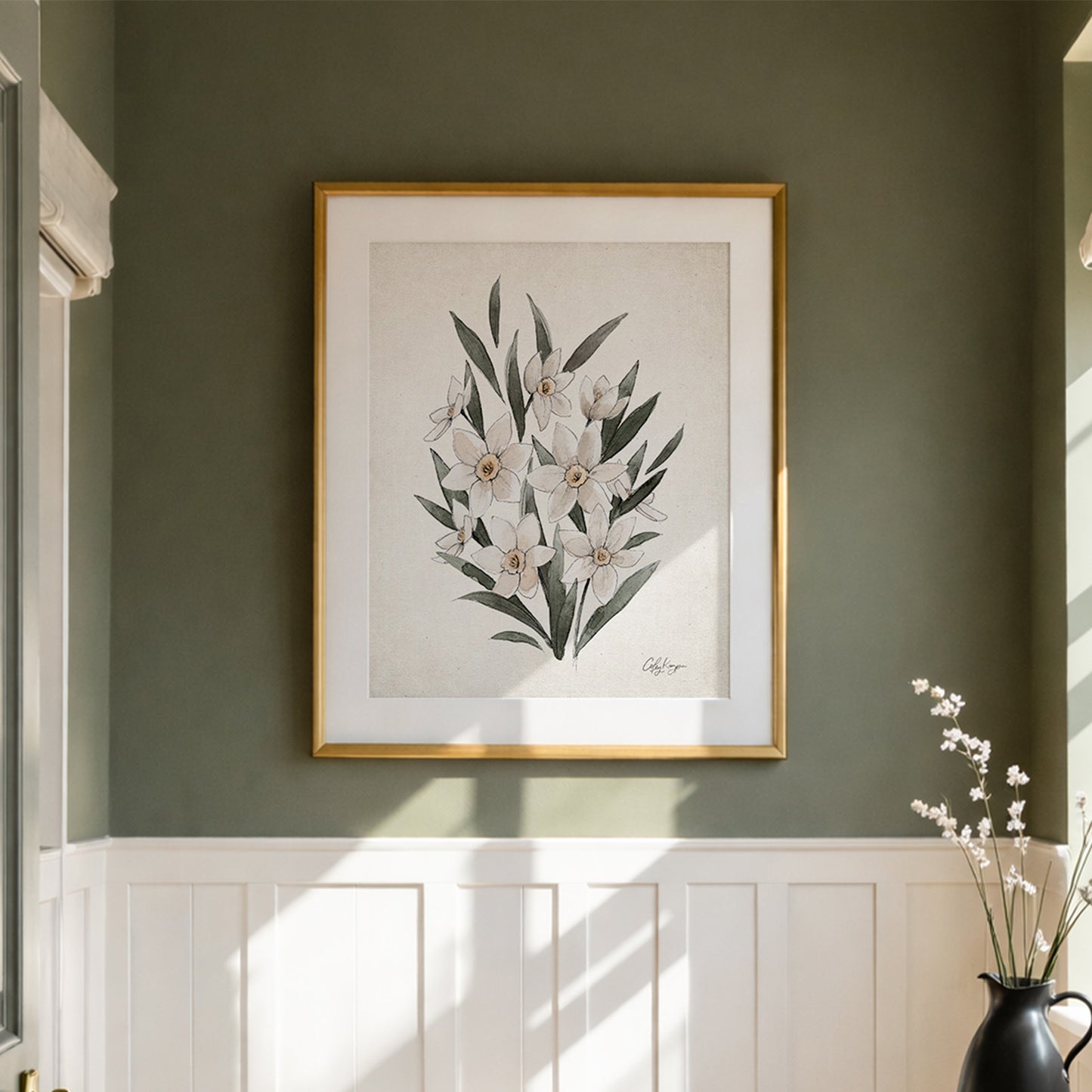 Framed March Daffodil birth flower wall art on neutral artwork on a wall with a vase of flowers below.