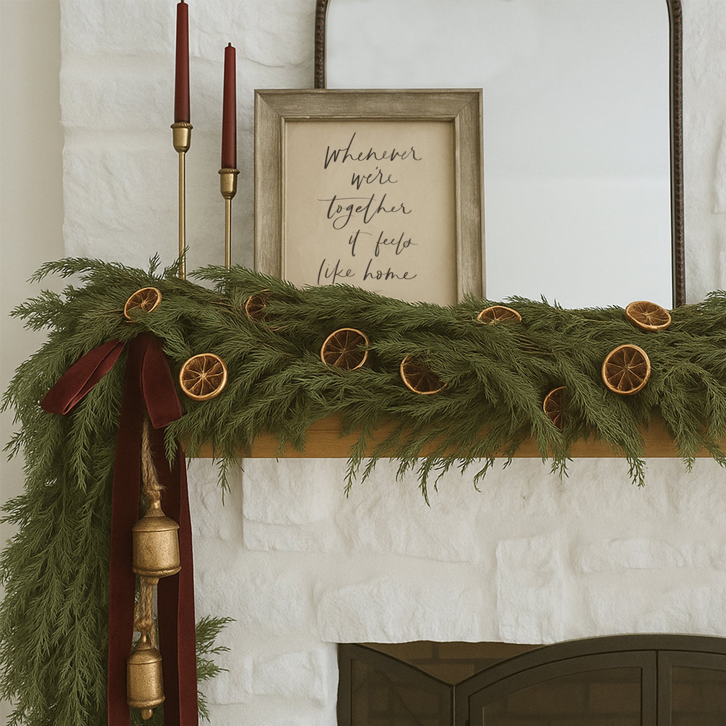 Decorative Christmas mantel with greenery, candles, and a framed quote on a white wall. Framed hand lettered family quote art print saying whenever were together