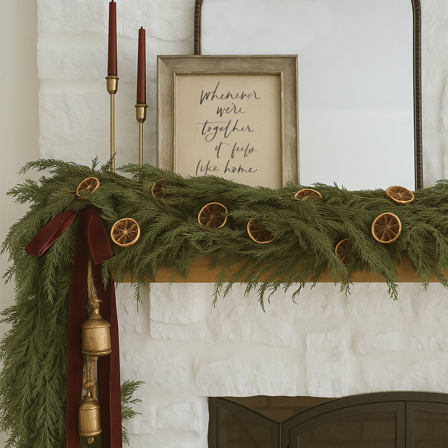 Decorative Christmas mantel with greenery, candles, and a framed quote on a white wall. Framed hand lettered family quote art print saying whenever were together