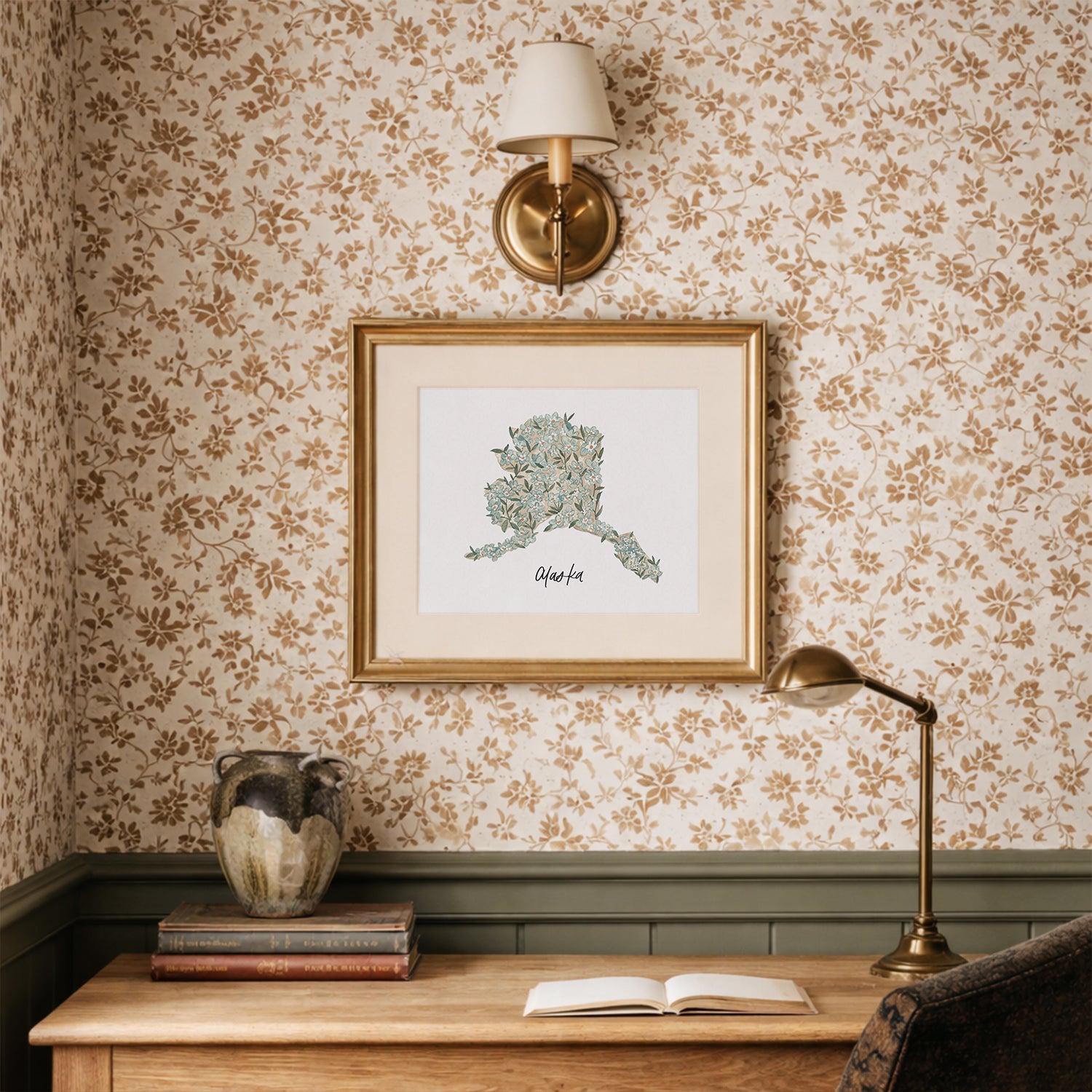 Decorative interior with floral wallpaper, framed Alaska state floral watercolor artwork, and a lamp.