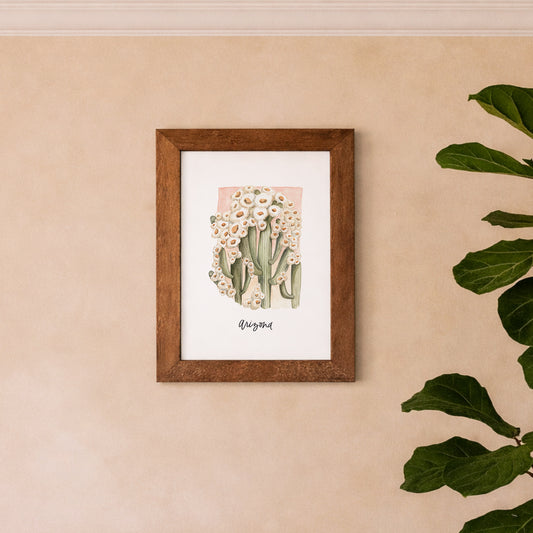 Arizona state flower Saguaro Cactus Blossom watercolor art print framed on a beige wall with a plant to the right.