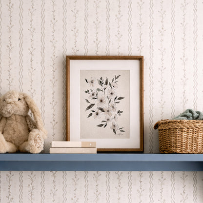 Framed February violet birth flower watercolor art print on a shelf with a teddy bear and basket against a patterned wall.