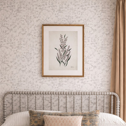 Framed July larkspur birth flower watercolor art print in soft purple, green, and neutral tones on a wall above a bed with floral headboard