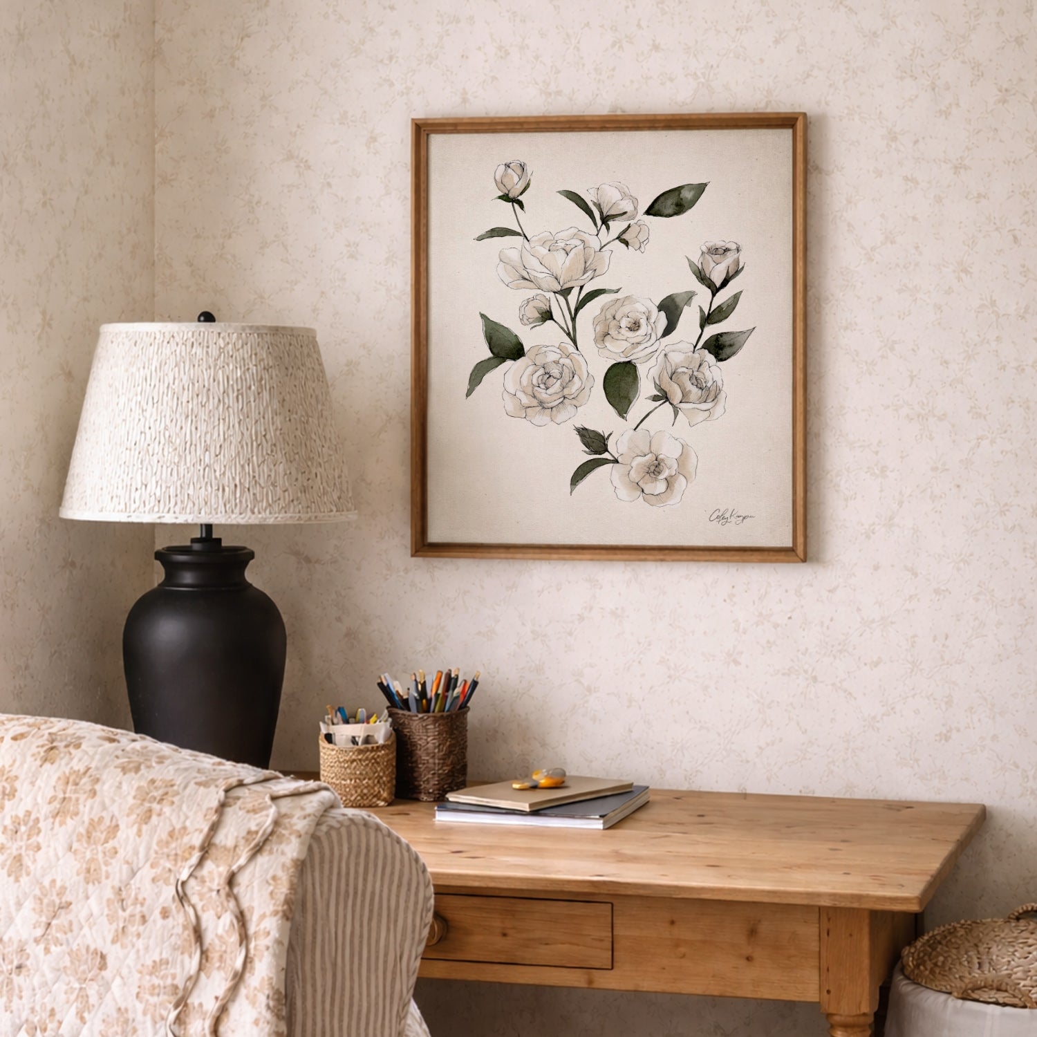 Decorative June rose birth flower watercolor art print on a wall above a wooden desk with a lamp and stationery items.