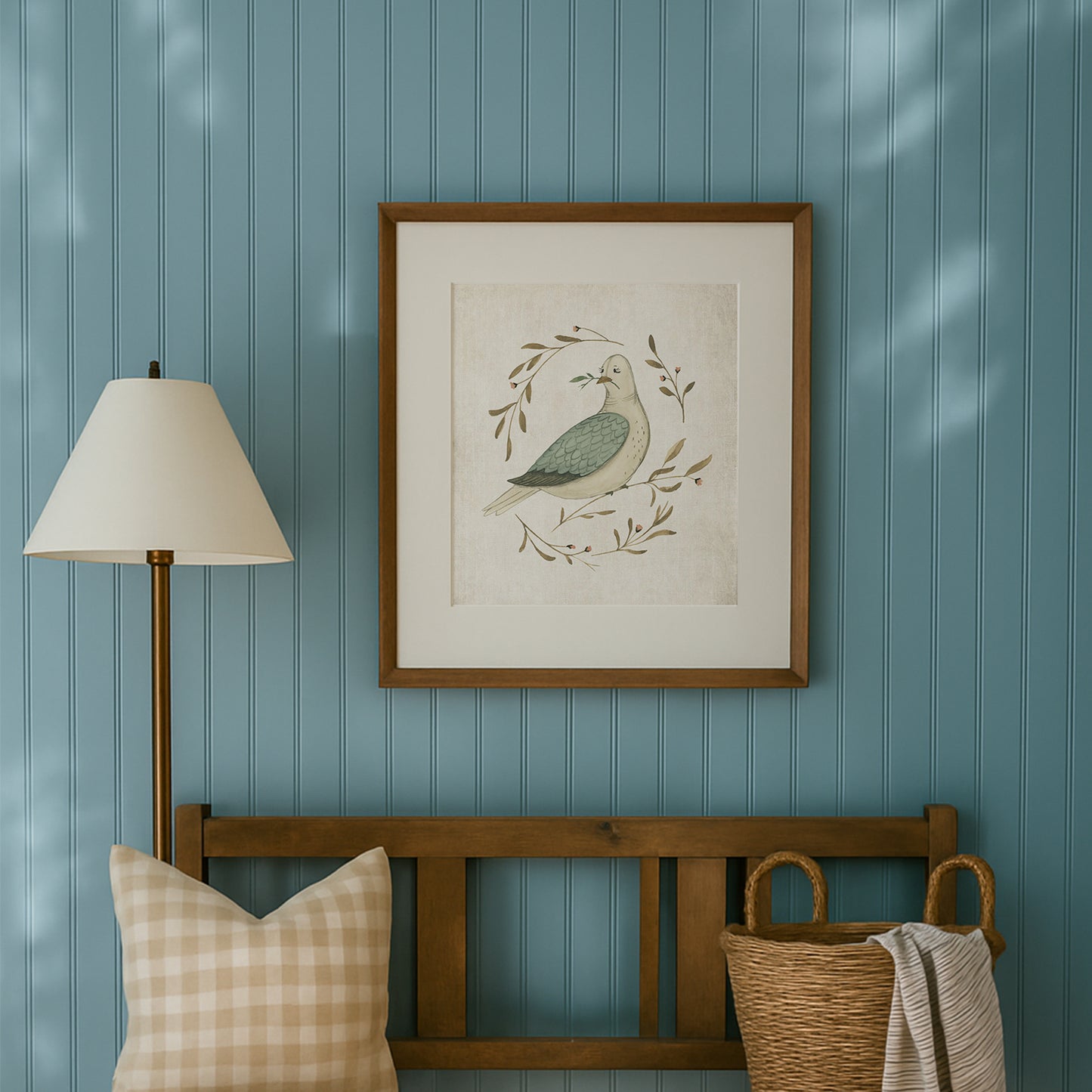 Framed artwork of a dove with leaves on a blue paneled wall above a wooden bench with a plaid pillow and woven basket. watercolor dove peace on earth christmas art print
